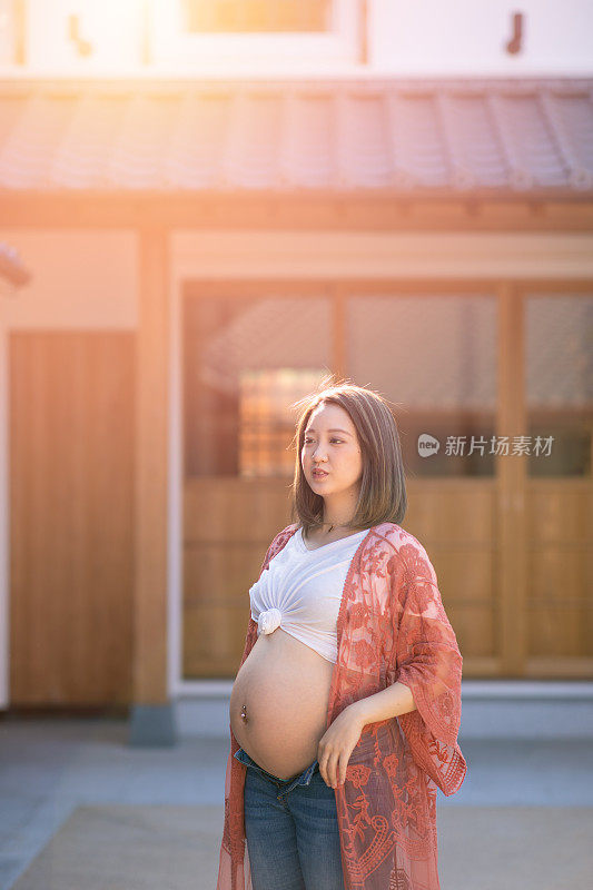 怀孕少女站在传统的日本小镇上