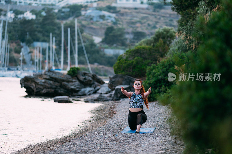 日落时分，年轻女子在海滩上做瑜伽