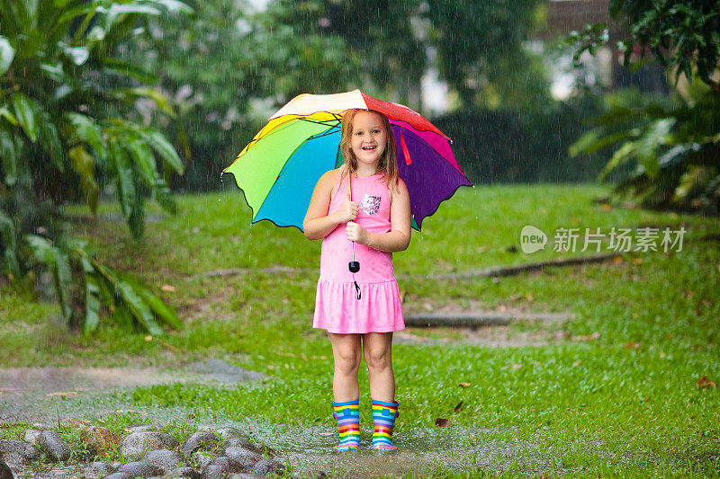孩子们撑着伞在夏日的雨中玩耍。