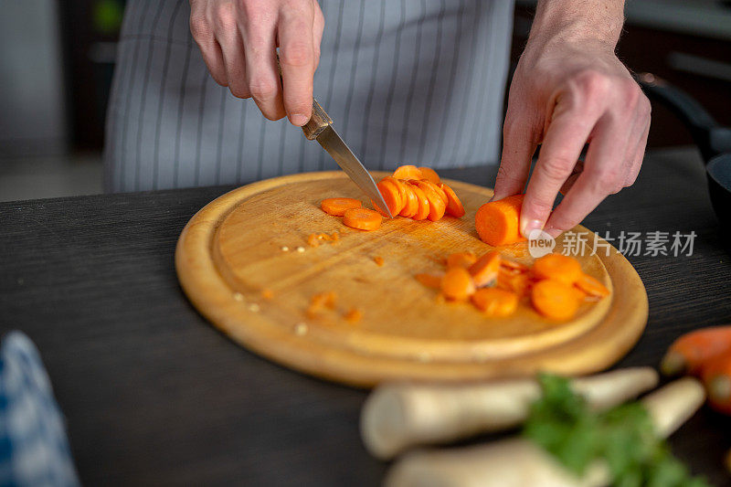 正在切胡萝卜的男人和一串新鲜的生胡萝卜