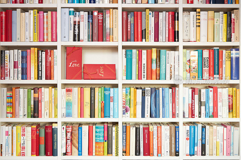 图书馆里，白色的书架上，五颜六色的书，一部分用红色的礼品包装，用爱心包装