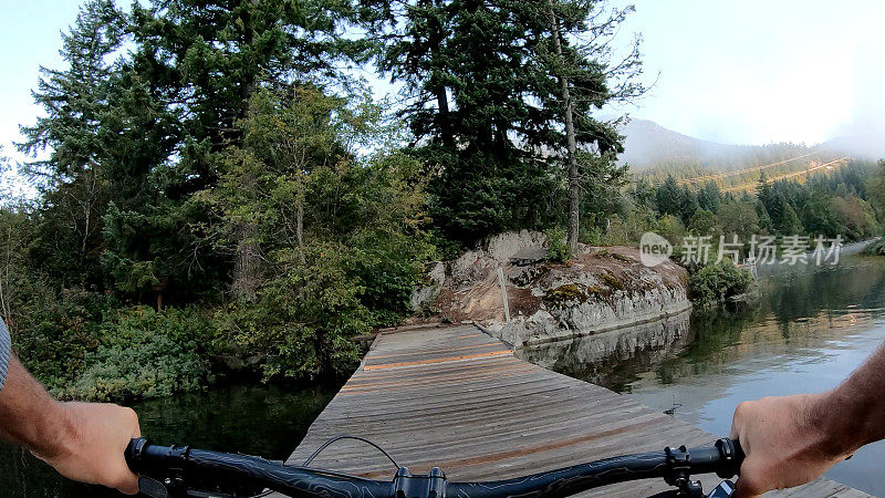 早上，一名男子沿着湖边的码头骑自行车