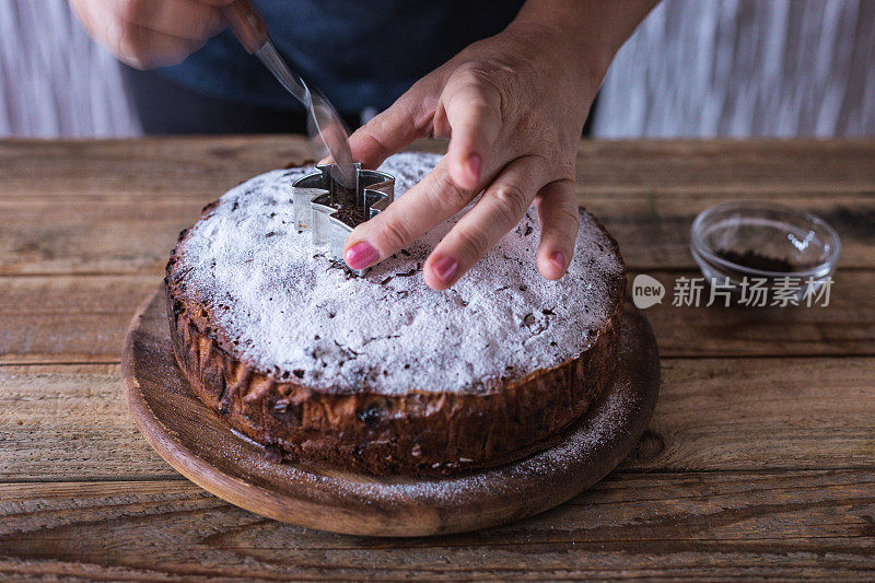 厨师用巧克力屑和松树形状的模具装饰新鲜制作的圣诞饼干