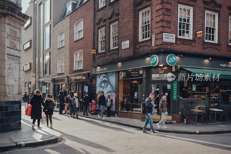 英国伦敦苏荷区的咖啡馆和餐馆，行人走过，动态模糊。