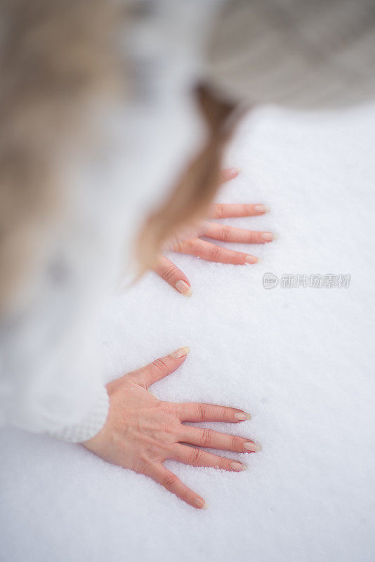 年轻女子在雪中留下手印，冬天