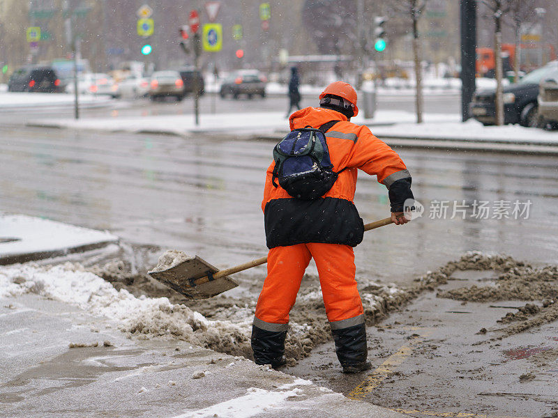 下雪后，工人在人行道上铲雪。