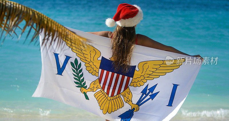 圣诞女孩在热带海滩上举着美属维尔京群岛的旗帜