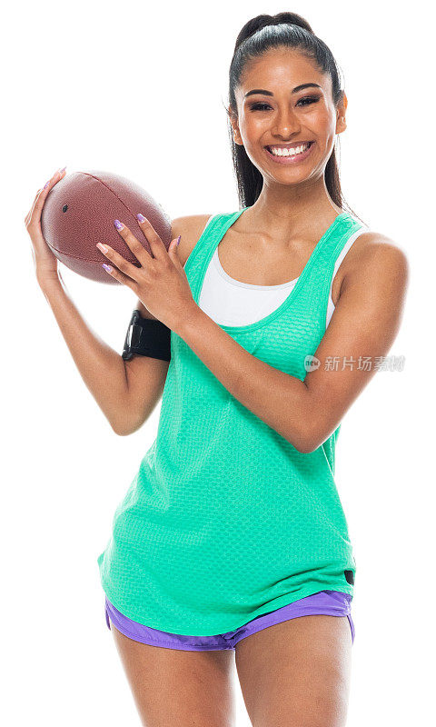 z一代的年轻女性穿着背心，用运动球站在黑色背景前无袖