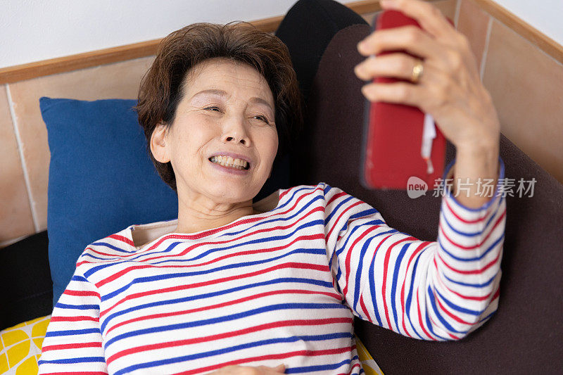 老女人躺在沙发上享受视频聊天