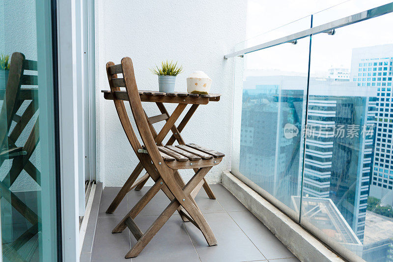 阳台上的木制桌椅俯瞰着现代化的大城市。舒适的阳台上。