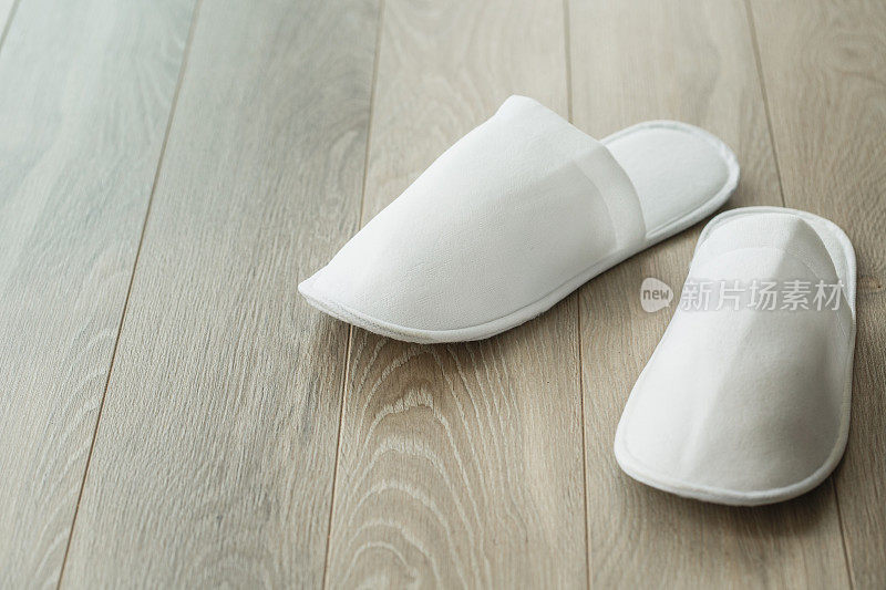 特写一双简单的白色拖鞋在木地板上