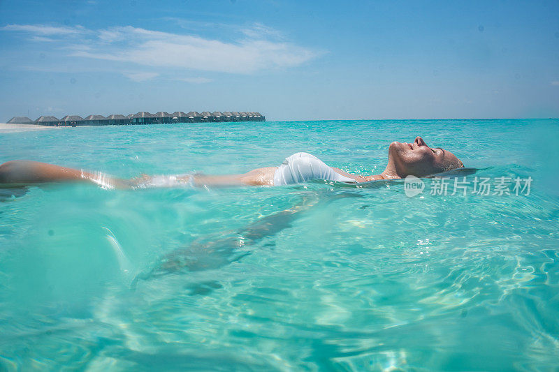 一个年轻的女人在热带海上漂浮