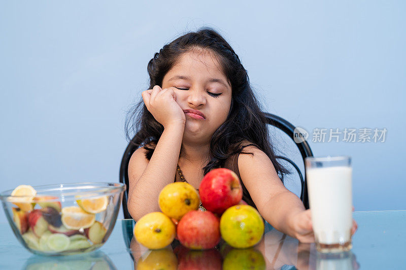 不高兴的小女孩不想早餐吃加牛奶的水果。