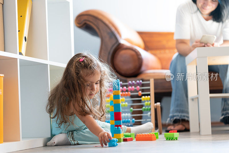 学龄前女孩在地板上玩玩具积木的照片