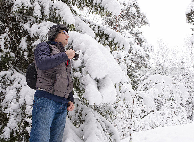 白种人在冬天的雪地里。那个人正在休息和喝咖啡。步行旅游。