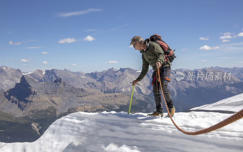 一位男性登山运动员到达了雪山的顶峰