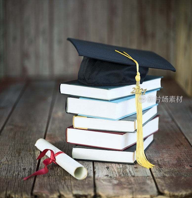 毕业帽和文凭概念上的一个木材背景