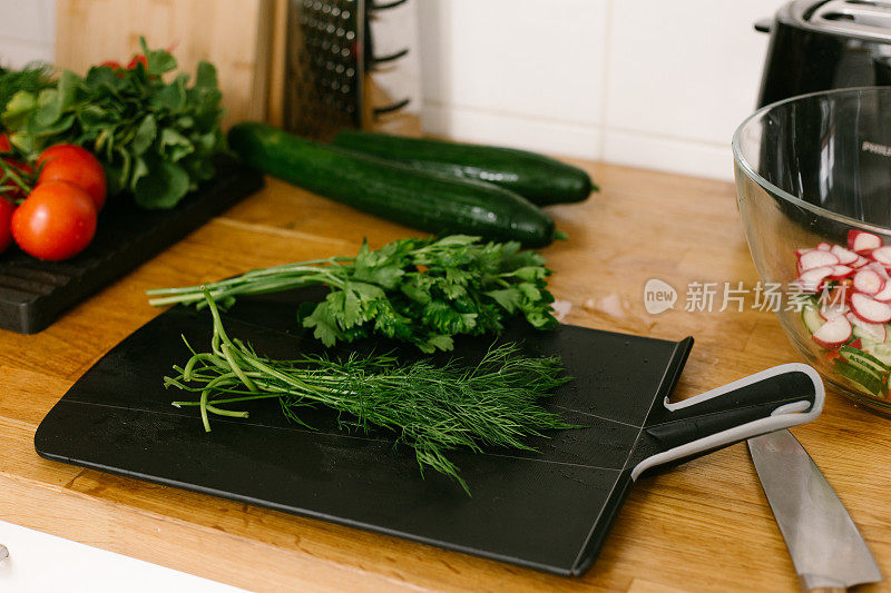 切碎的欧芹和小茴香放在木桌上的砧板上