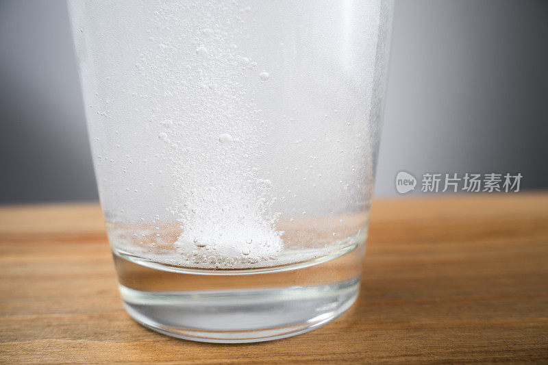 在白色的背景下，将溶解的药片放入一杯水中。