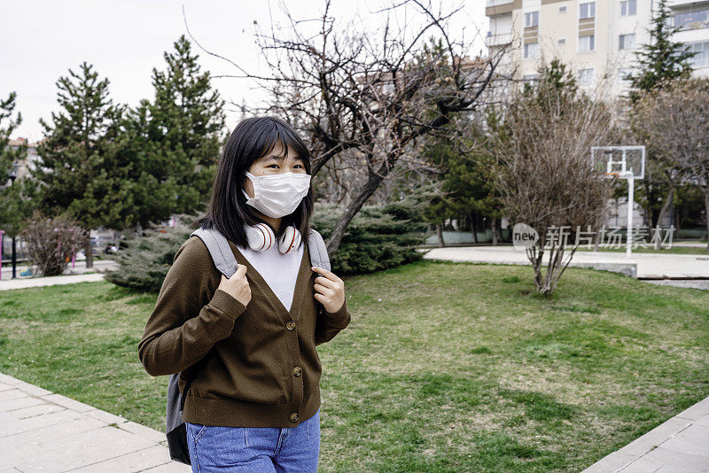 回到学校。日本血统的女孩在校园里。她戴着防护口罩。