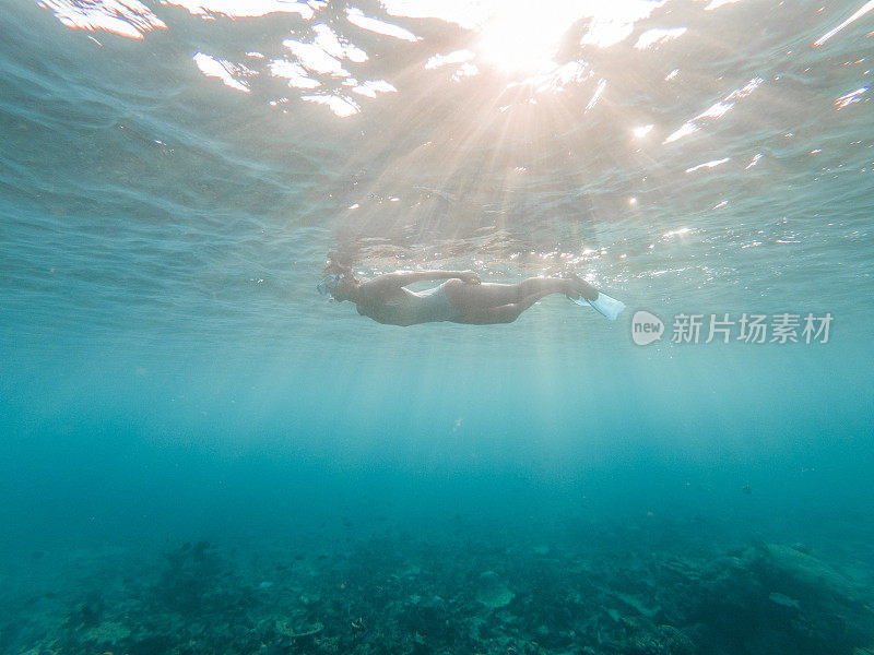 女子浮潜在热带海域，水下拍摄阳光