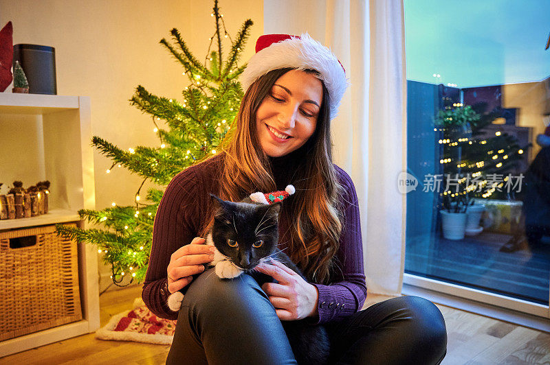 一个年轻女子和她的猫坐在地板上庆祝圣诞节的照片