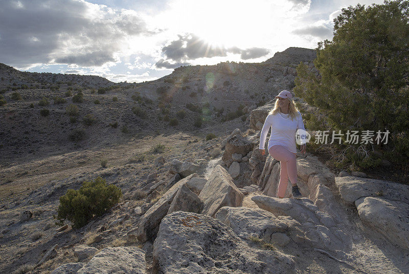 清晨，一名女子沿着沙漠小径徒步旅行