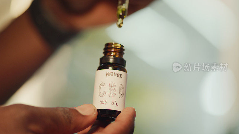 医用大麻的研究。非洲科学家拿着一个装有CBD油的玻璃瓶