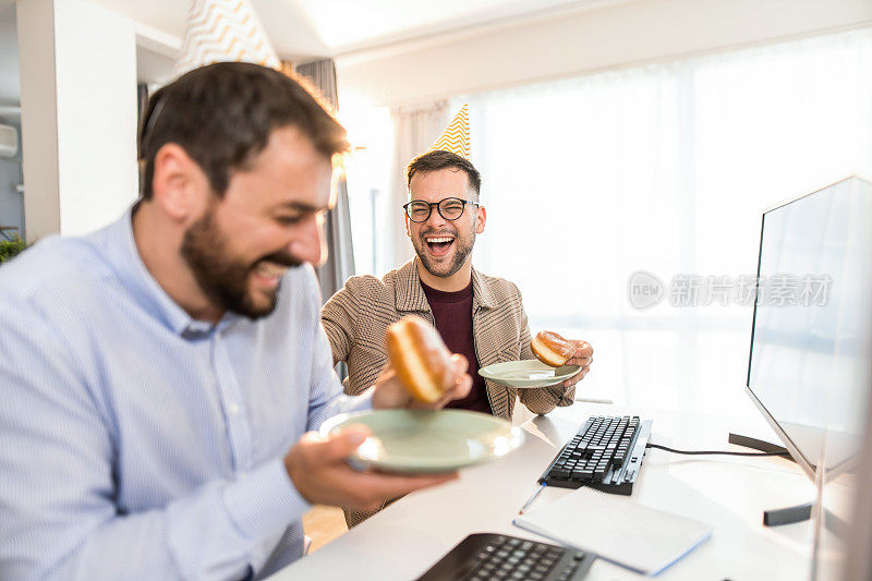 两个友好的生意伙伴在办公室庆祝生日。