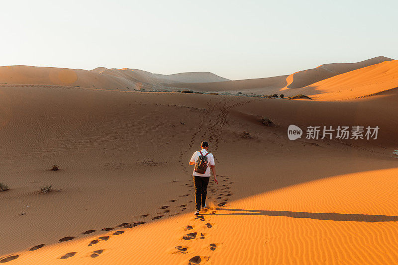 在纳米比亚索苏瓦莱的明亮的日出期间，男子旅行者探索风景优美的沙漠景观