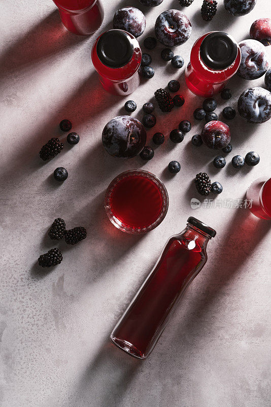红色果汁与黑莓和李子在厨房的工作台上