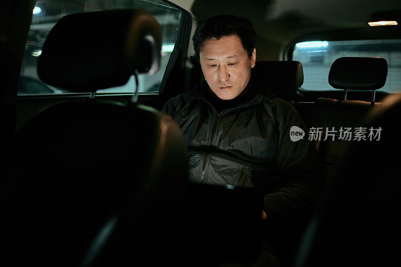 在上班的路上，亚洲男性在汽车后座使用笔记本电脑