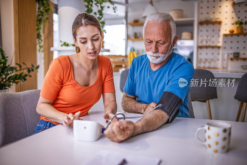 女儿在家里给父亲量血压。