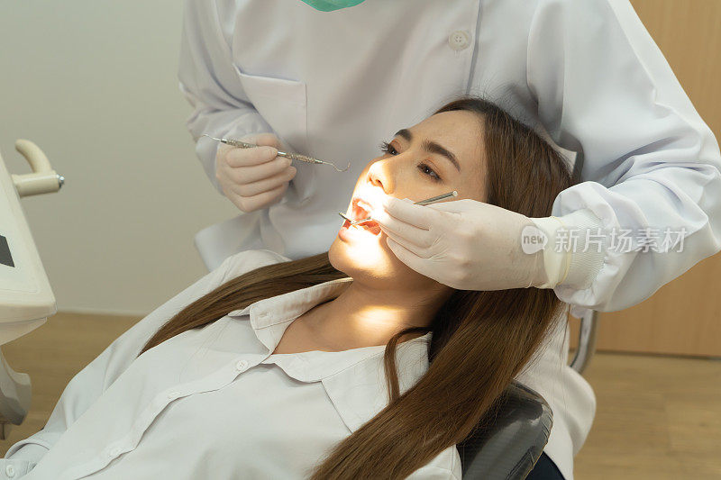 一位牙医在医院诊所用口腔镜检查亚洲妇女的牙齿。牙齿检查。牙科工具。医生。牙医。医疗和牙科健康。人。