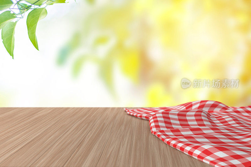 空木桌，凌乱的桌布，模糊的绿色自然背景。