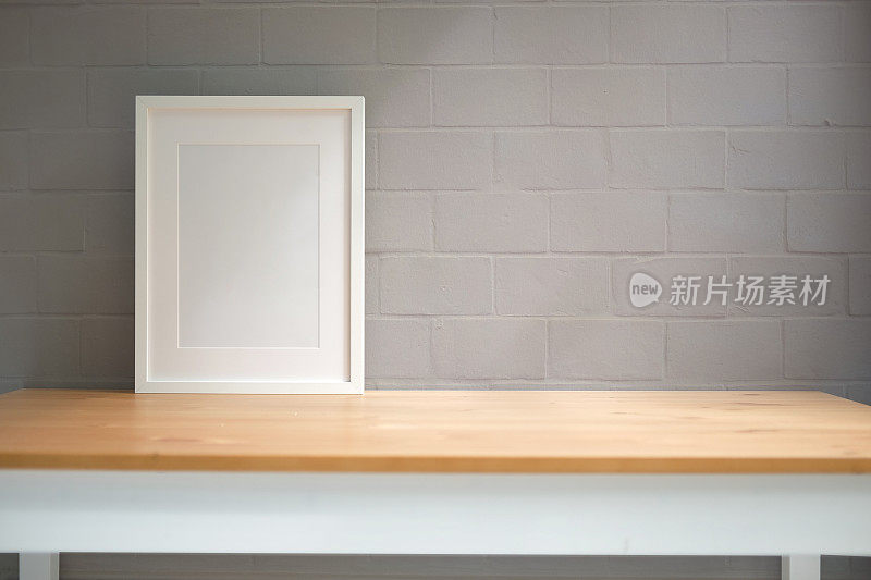 木桌和砖墙上的空相框。复制空间为您的广告文本。