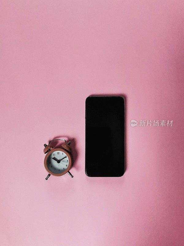 在粉红色的背景下，一个粉色的时钟和一个空白的智能手机屏幕，一个空白的复制空间，一个原型的创意