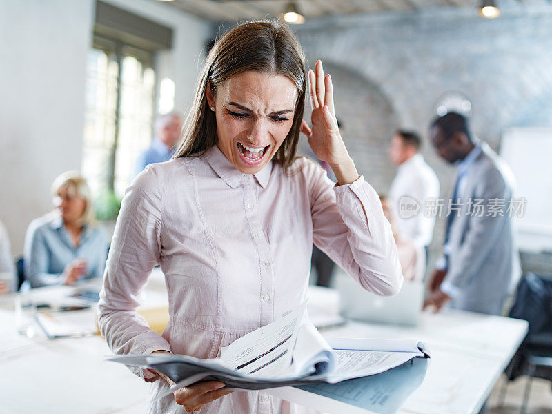 失意的女商人在办公室读着令人震惊的报告。