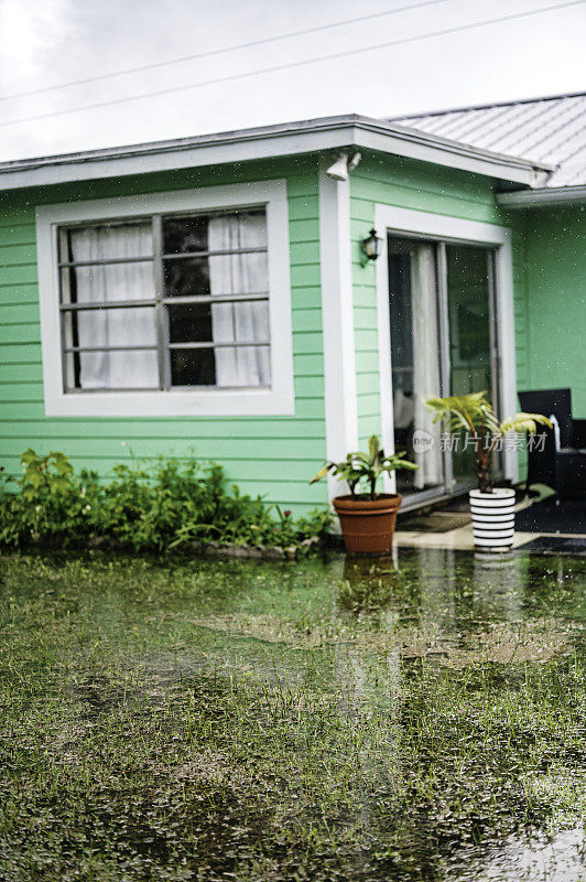 暴雨袭击了一个独栋房屋的屋顶，屋顶上有排水沟，热带风暴淹没了院子