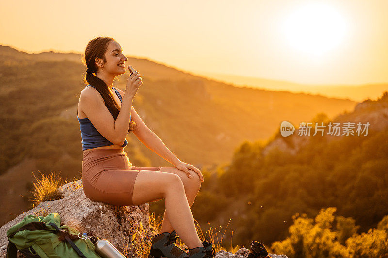 徒步旅行后在山上吃点心的年轻女子