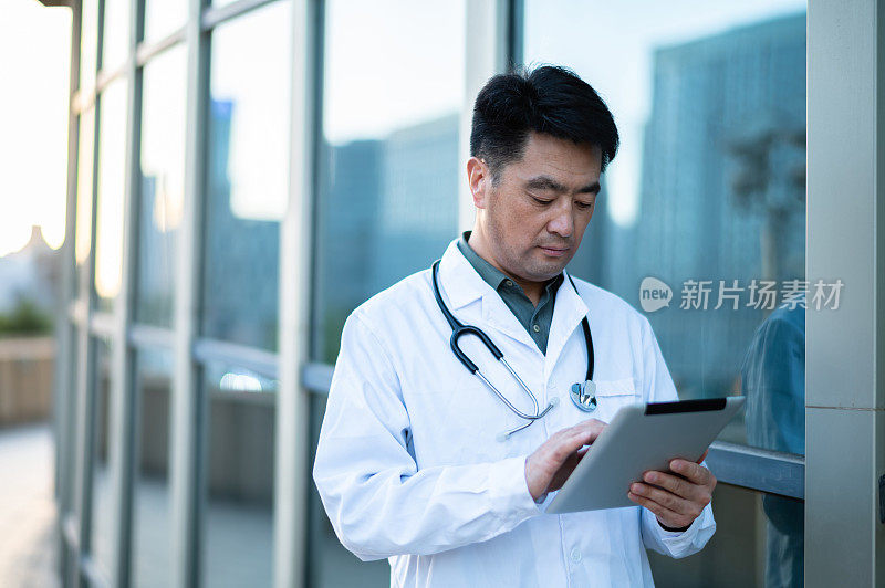 亚洲中年男医生在医院使用数字平板电脑