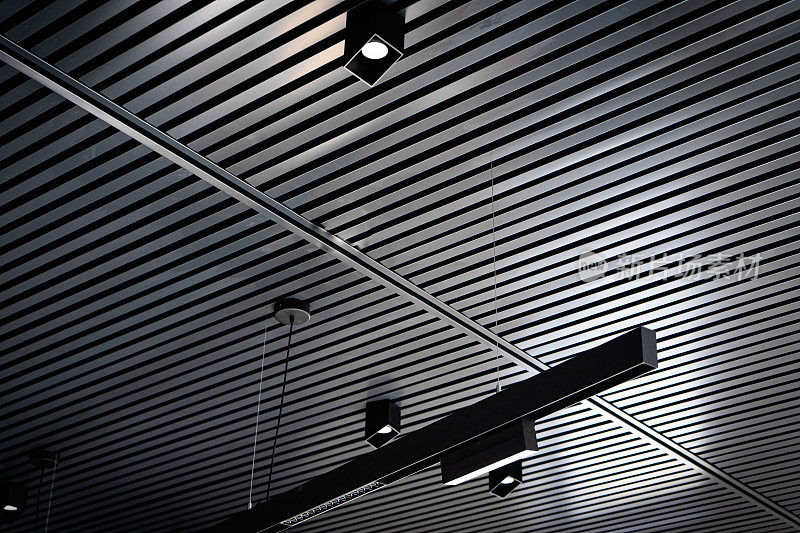 带射灯的板条天花板的底部视图。抽象现代建筑或室内背景采用黑白几何结构。