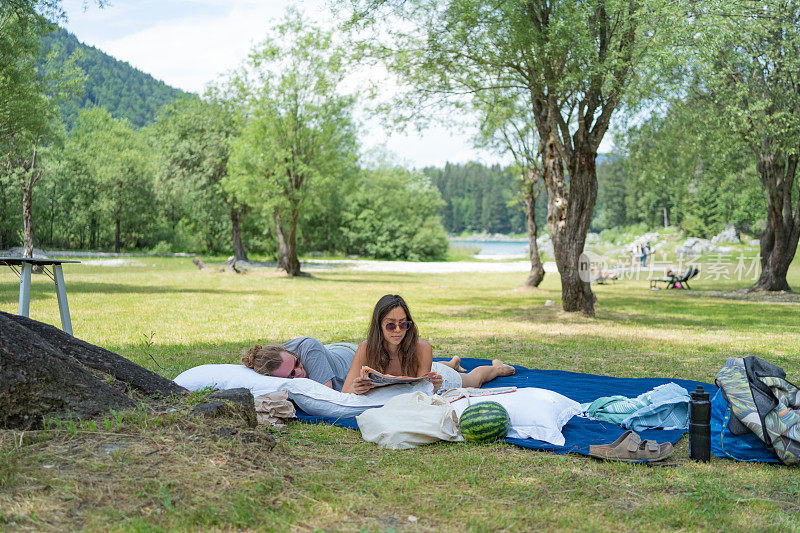一对夫妇在野餐毯上休息，在草地上