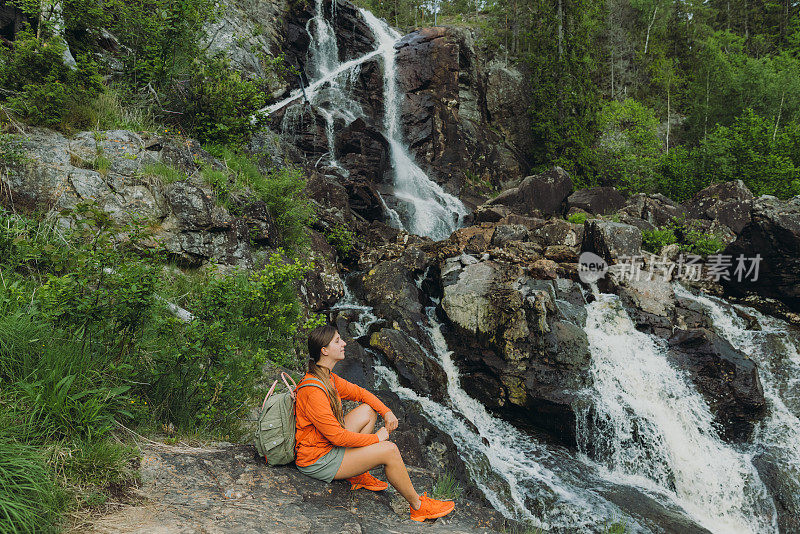 背着双肩包的女性凝视着瑞典美丽的瀑布