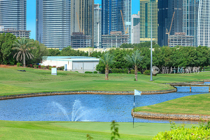 迪拜，阿拉伯联合酋长国——前景是高尔夫球道，背景是朱美拉湖塔楼地区的现代摩天大楼