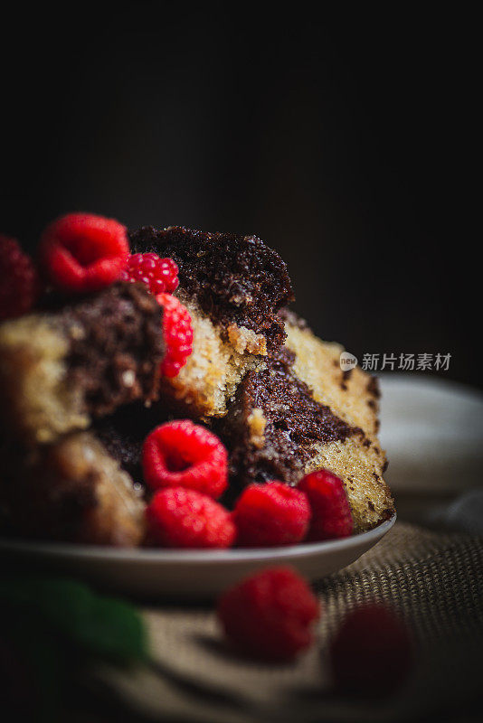 两个口味的海绵蛋糕和覆盆子的特写细节，在木桌和旧的白色抹布上，木制底座，复制空间。