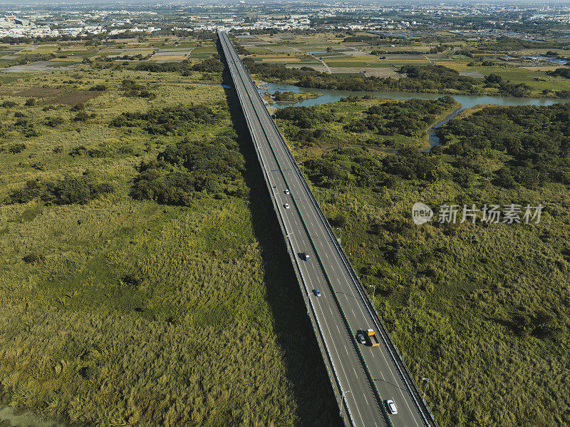 汽车在高速公路路口行驶的鸟瞰图。桥梁道路与绿色花园和树木连接的建筑概念