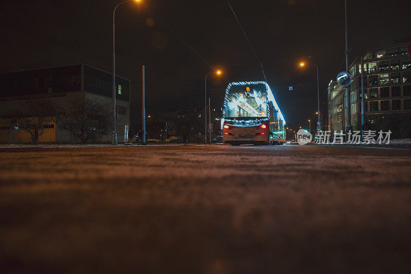 灯火通明的公共汽车在夜晚的城市街道上快速行驶