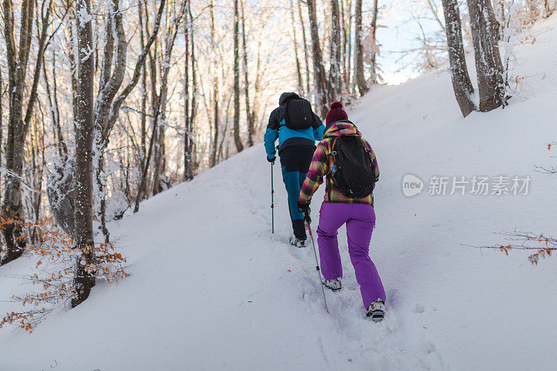 两个年轻的徒步旅行者在冬天爬上雪山