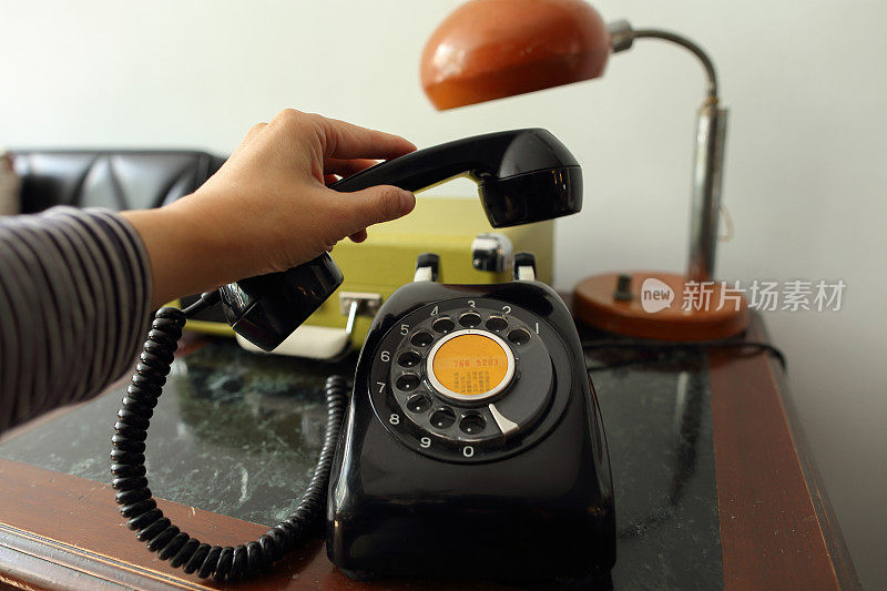 一只手正准备放回一部黑色古董拨号电话的听筒